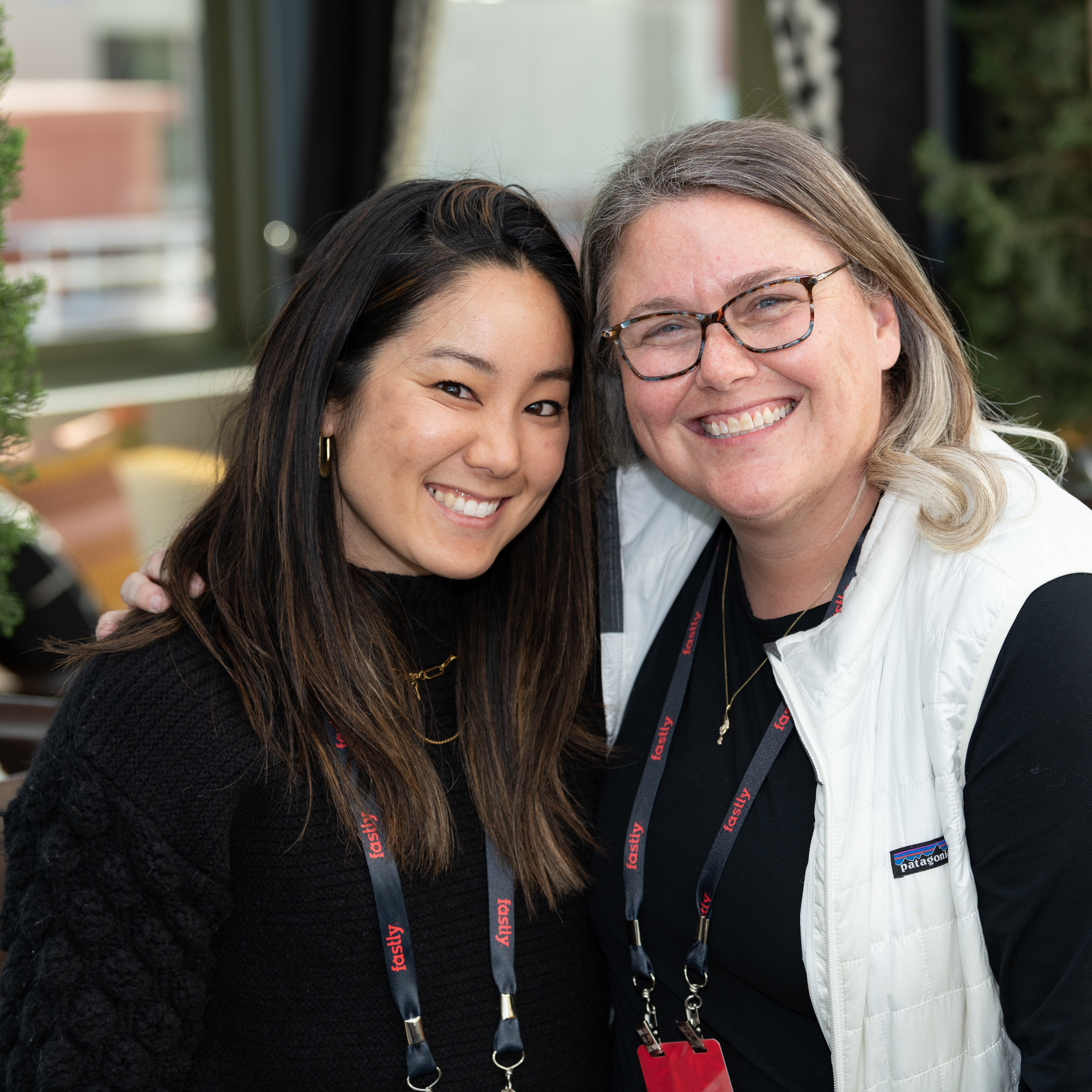 Two Fastly employees smiling with their arms around each other
